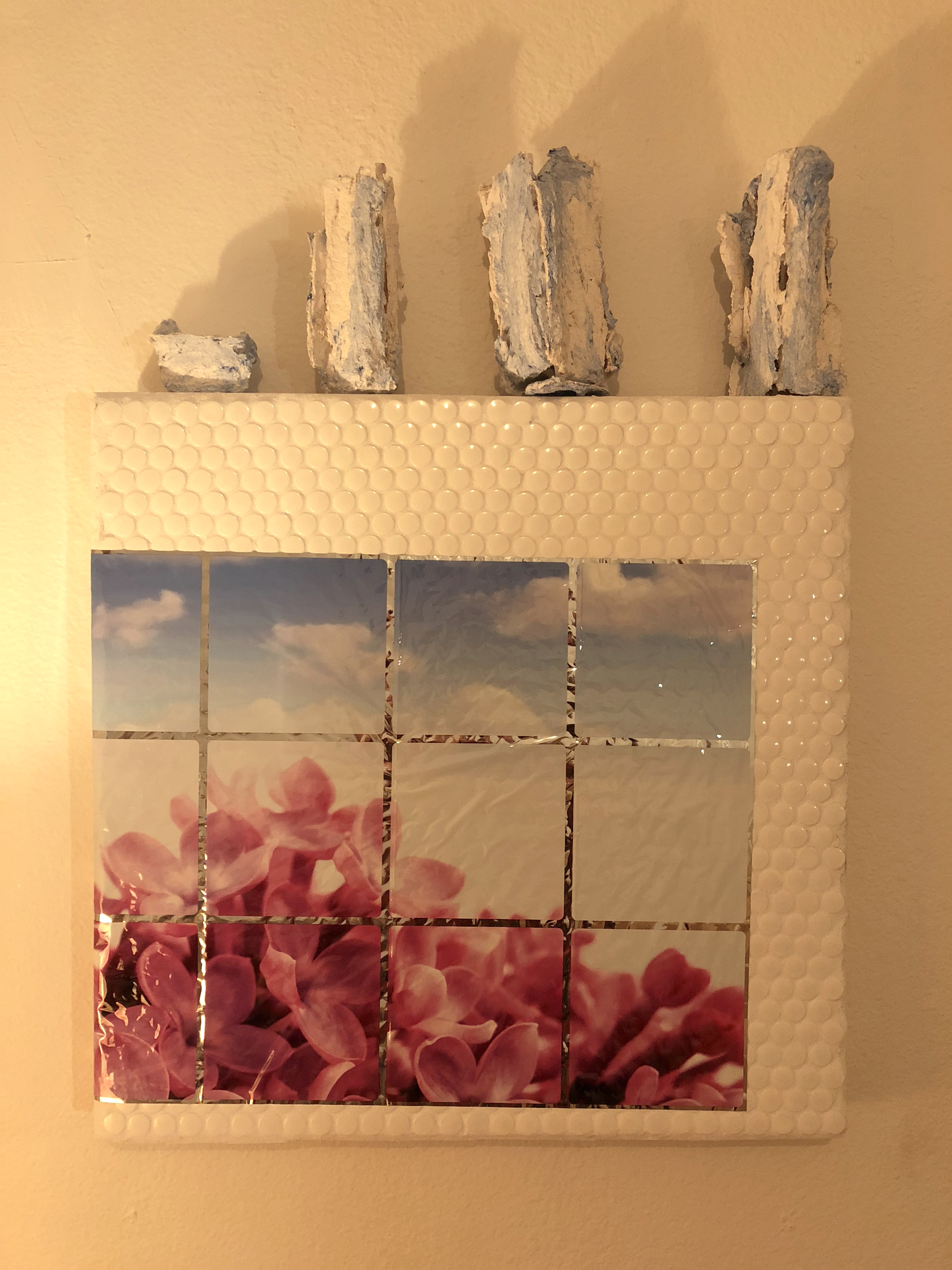Tiled wall sculpture with a photographic print of flowers on it hung on a white wall